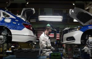 A WORKER ON AN ASSEMBLY LINE BUILDS AN ELECTRIC VEHICLE 