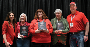 Three women holding award plaques