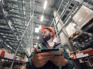 An employee uses a digital tablet in a warehouse. 
