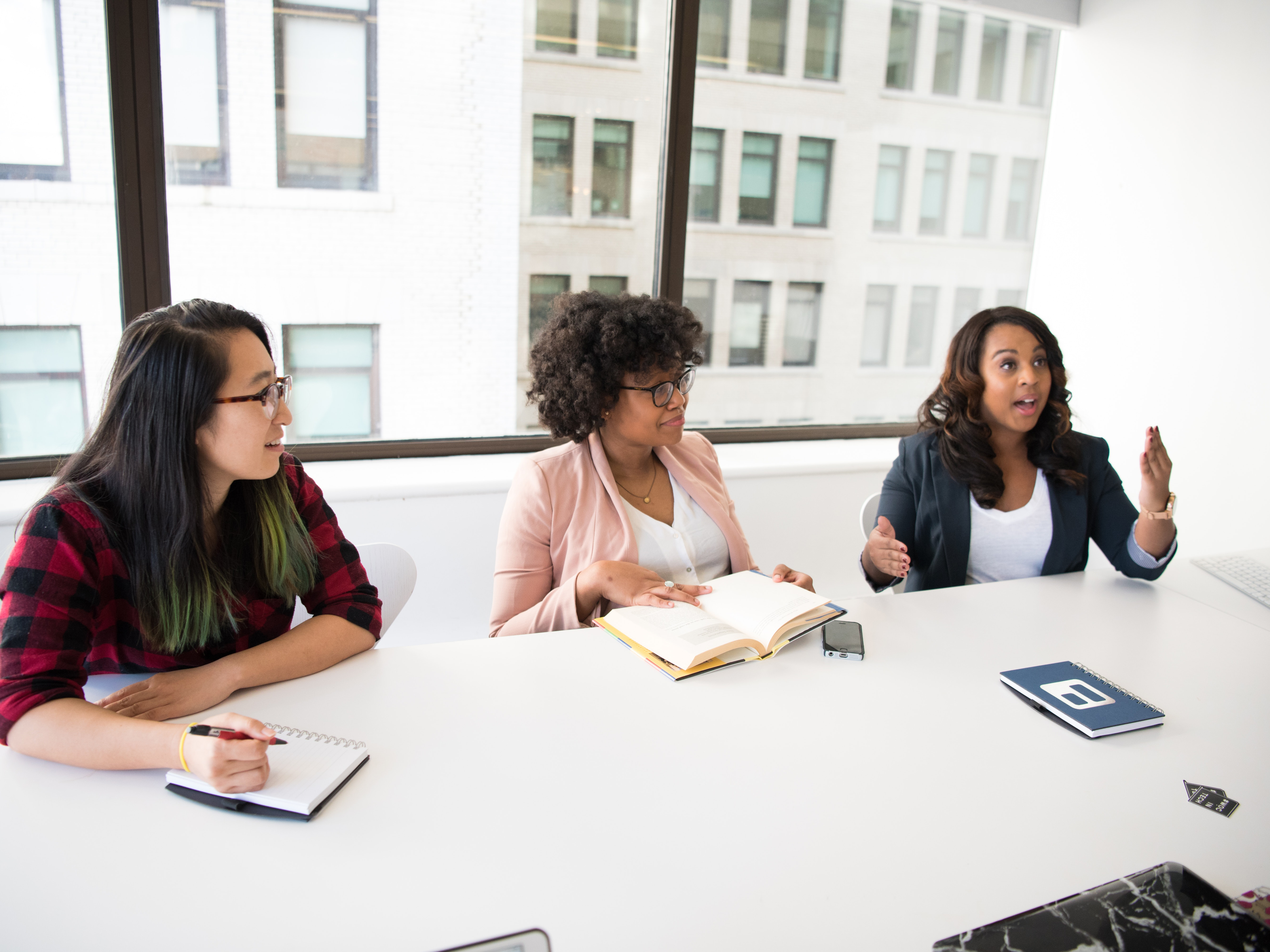 Women of color gather in an office. 