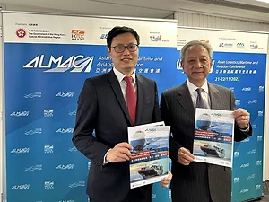 Two men holding publications with ALMCA backdrop