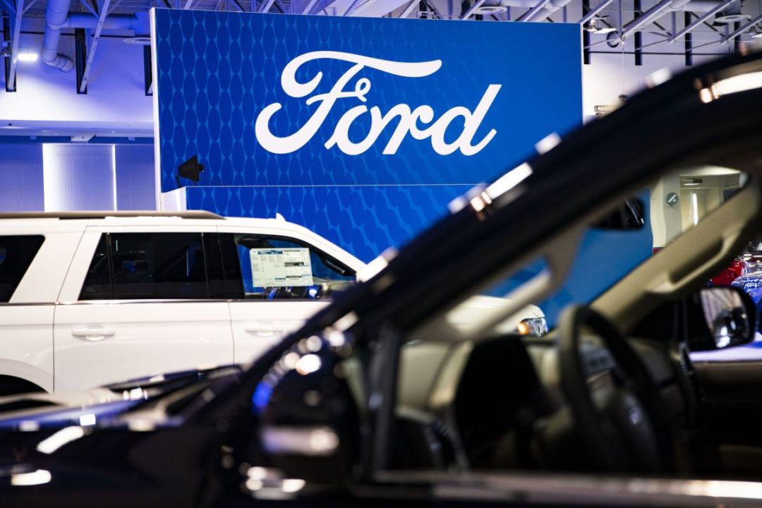 PHOTO OF TWO CARS WITH FORD LOGO IN BACKGROUND BLOOMBERG