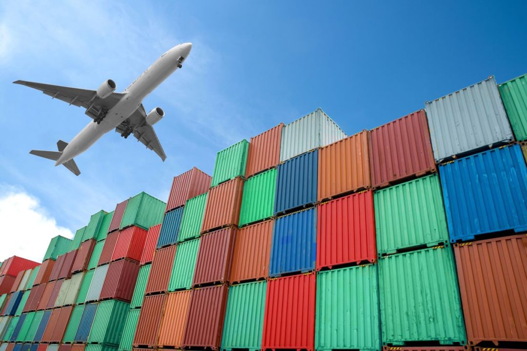 A PLANE FLIES OVER A STACK OF SHIPPING CONTAINERS iStock-ake1150sb-504606896.jpg