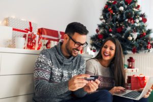 TWO PEOPLE IN A LIVING ROOM SURROUNDED BY HOLIDAY DECORATIONS LOOK INTO A TABLET, SMILINGiStock-891523968.jpg