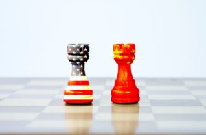 TWO CHESS PIECES, BEARING THE COLORS OF THE US AND CHINESE FLAGS, SIT ON A BOARD