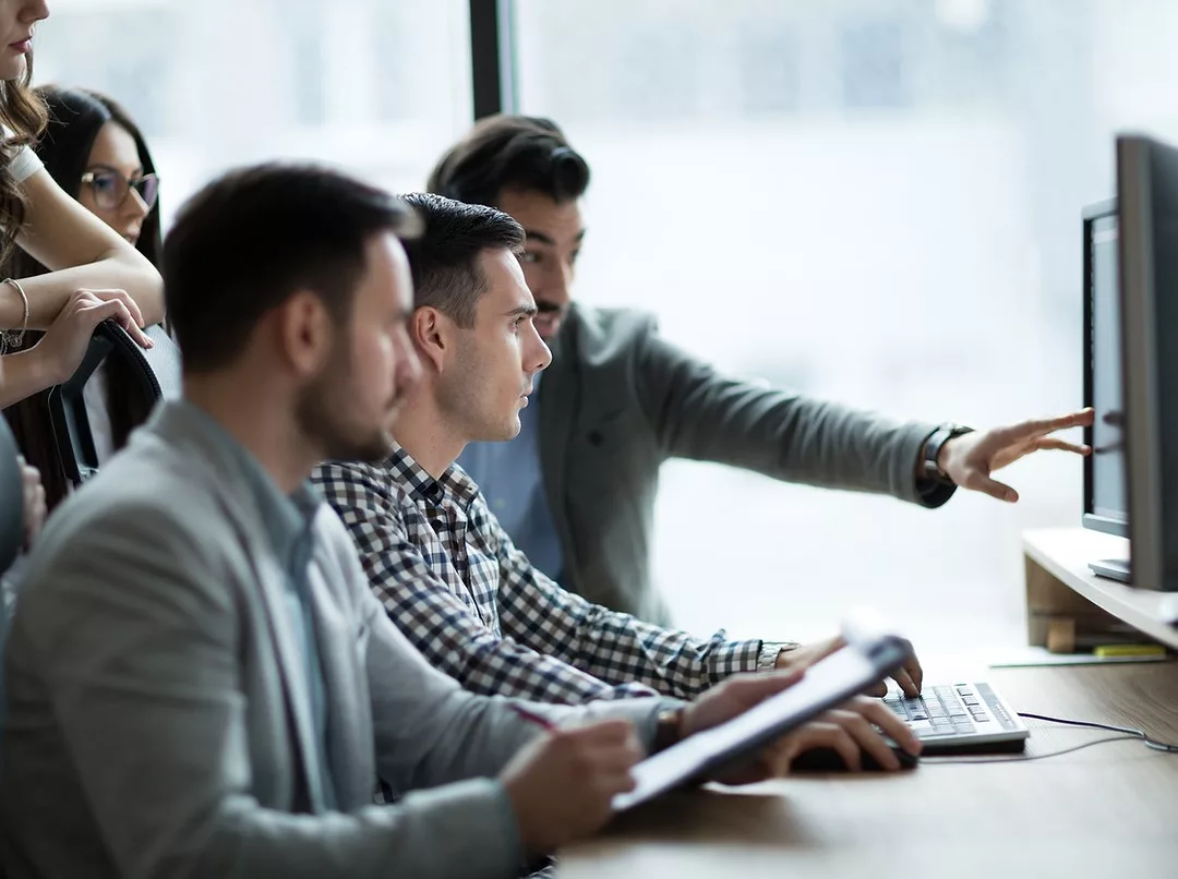 A TEAM OF PEOPLE RECEIVES DIGITAL TRAINING IN AN OFFICE