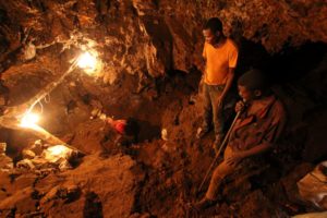 Three young African miners work in an underground mine and dig for reseources.
