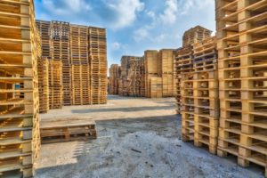 STACKS OF WOODEN SHIPPING PALLETS IN A YARD, AWAITING RECYCLING