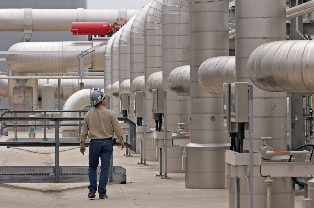 A WORKER WALKS AMONG GIANT PIPES AT FREEPORT LNG TEXAS
