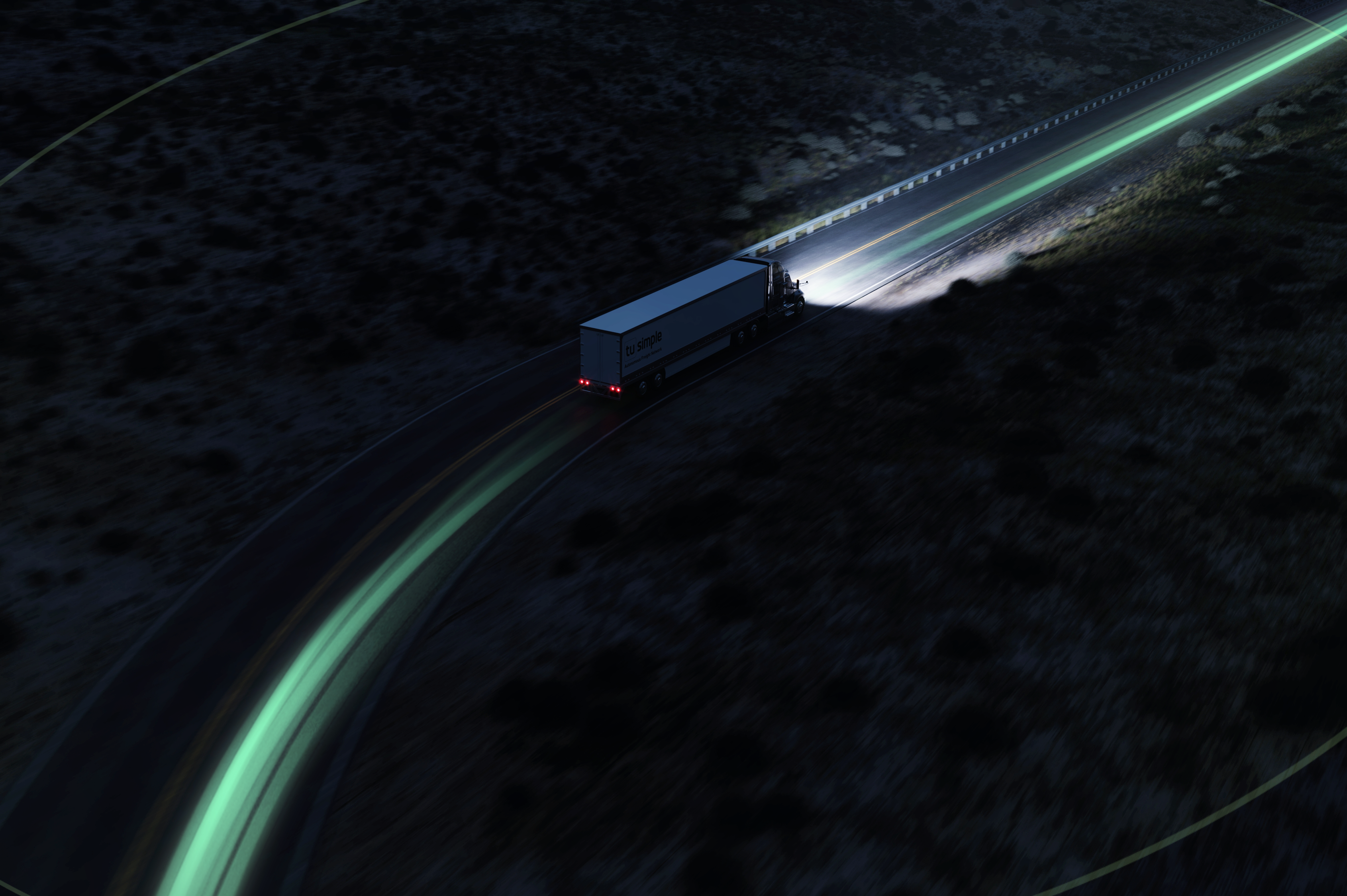 A TuSimple TRUCK DRIVES DOWN THE HIGHWAY AT NIGHT