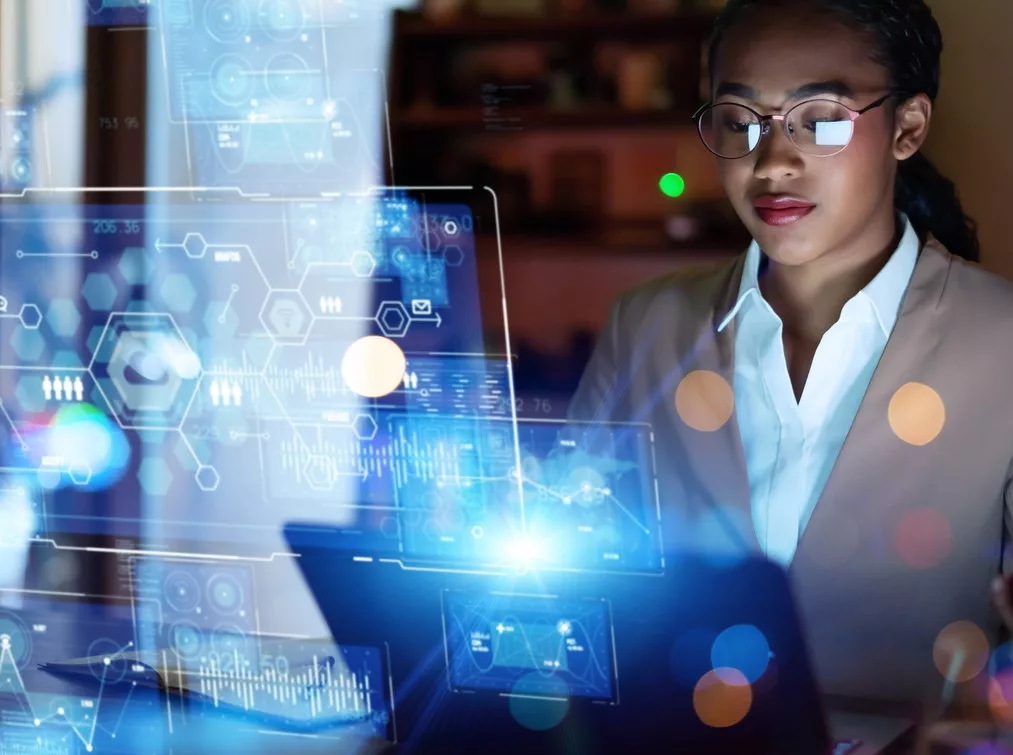 A WORKER WORKS AT A LAPTOP, SURROUNDED BY DIGITAL TRANSFORMATION GRAPHICS