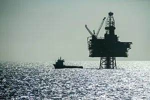 AN OFFSHORE OIL RIG STANDS SILHOUETTED BY THE SHINING LIGHT OF THE NORTH SEA 