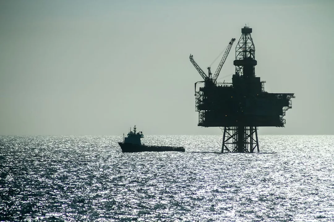 AN OFFSHORE OIL RIG STANDS SILHOUETTED BY THE SHINING LIGHT OF THE NORTH SEA