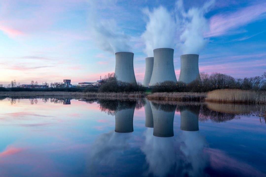 A NUCLEAR POWER PLANT SILHOUETTED AT DUSK BY A BODY OF WATER