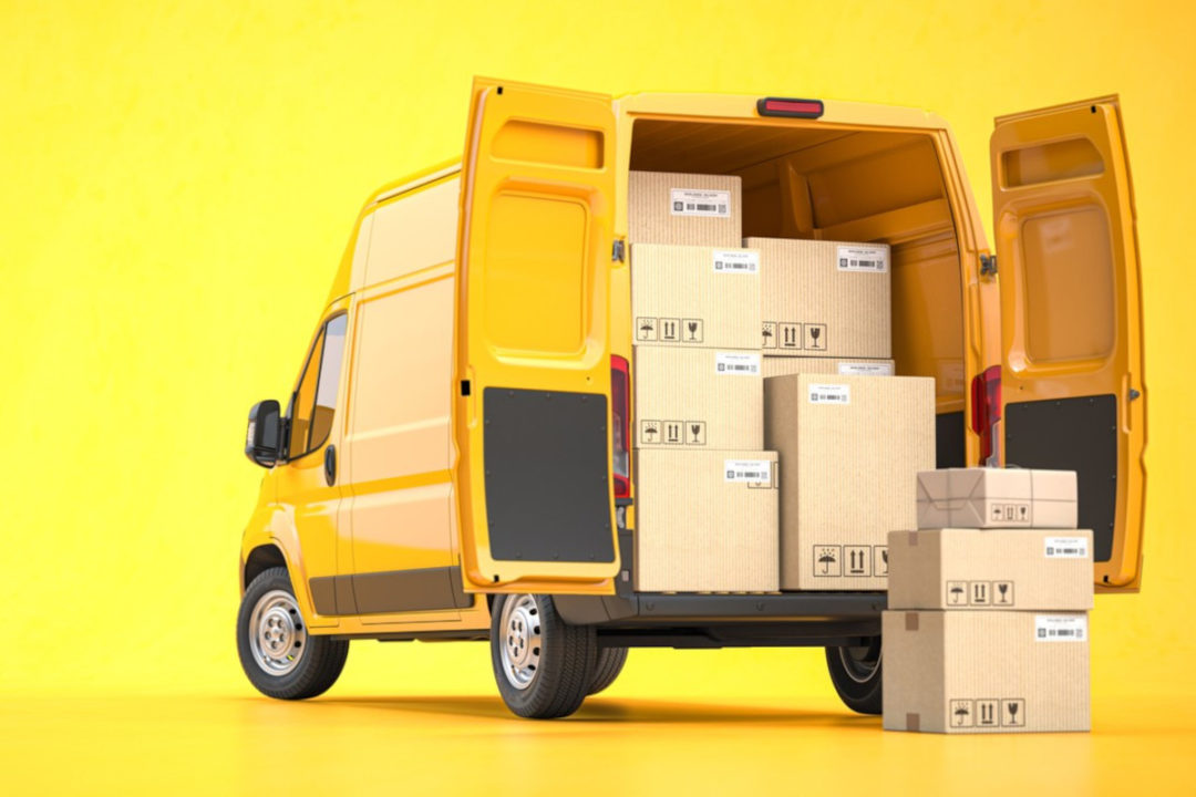 A BRIGHT YELLOW DELIVERY VAN STANDS WITH ITS DOORS OPEN, PACKAGES VISIBLE INSIDE