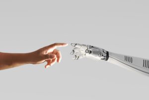A ROBOT ARM AND A HUMAN ARM ALMOST TOUCH FINGERS