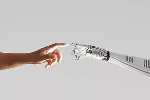 A ROBOT ARM AND A HUMAN ARM ALMOST TOUCH FINGERS