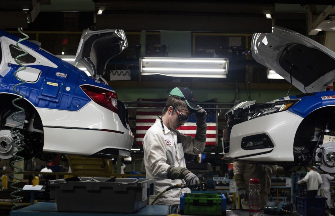 A WORKER BUILDS AN ELECTRIC VEHICLE ON AN ASSEMBLY LINE