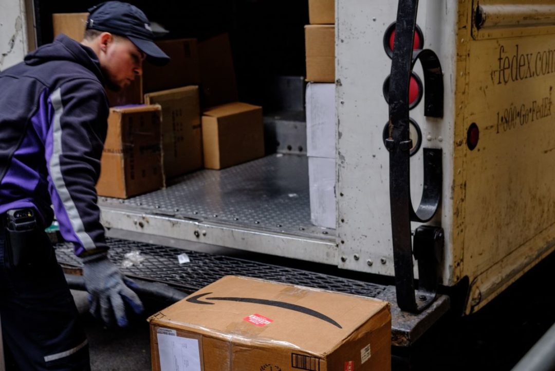 A FEDEX WORKER UNLOADS BOXES FROM A FEDEX TRUCK