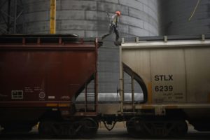 A worker walks across the top of a railroad grain hopper car at the Kokomo Grain Co. Inc. transloading facility in Edinburgh, Indiana