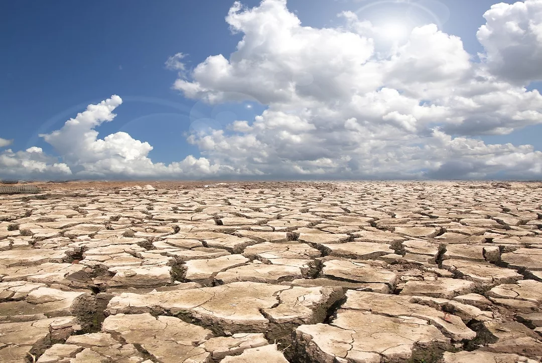 DEEPLY CRACKED EARTH UNDER A BLUE CLOUDY SKY
