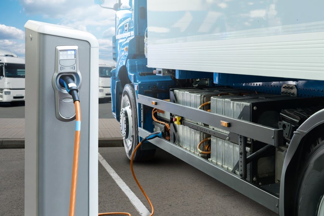 AN ELECTRIC TRUCK CHARGES AT A CHARGING STATION