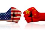 TWO CLENCHED FISTS FACE EACH OTHER, ONE PAINTED WITH THE US FLAG, THE OTHER WITH THE FLAG OF CHINA