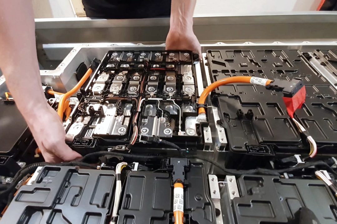 A WORKER HANDLES AN ELECTRIC VEHICLE BATTERY INTO PLACE