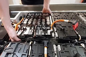 A WORKER HANDLES AN ELECTRIC VEHICLE BATTERY INTO PLACE