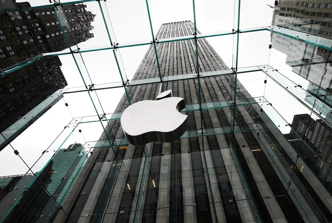 THE EXTERIOR OF AN APPLE OFFICE, THE COMPANY LOGO REFLECTED IN GLASS