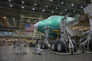 THE NOSE OF A GREEN BOEING 747 IS VISIBLE AMONG SCAFFOLDING IN AN AIRCRAFT HANGAR