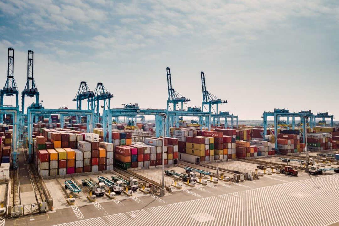 AERIAL PHOTO OF CONTAINER PORT WITH BLUE CRANES AND MULTI-COLORED CONTAINERS ON THE DOCK