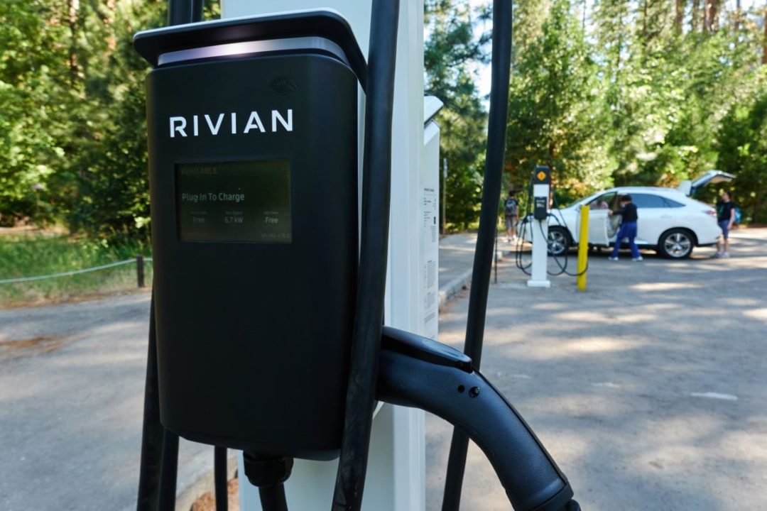 A RIVIAN CHARGING STATION STANDS READY AT A GAS STATION.