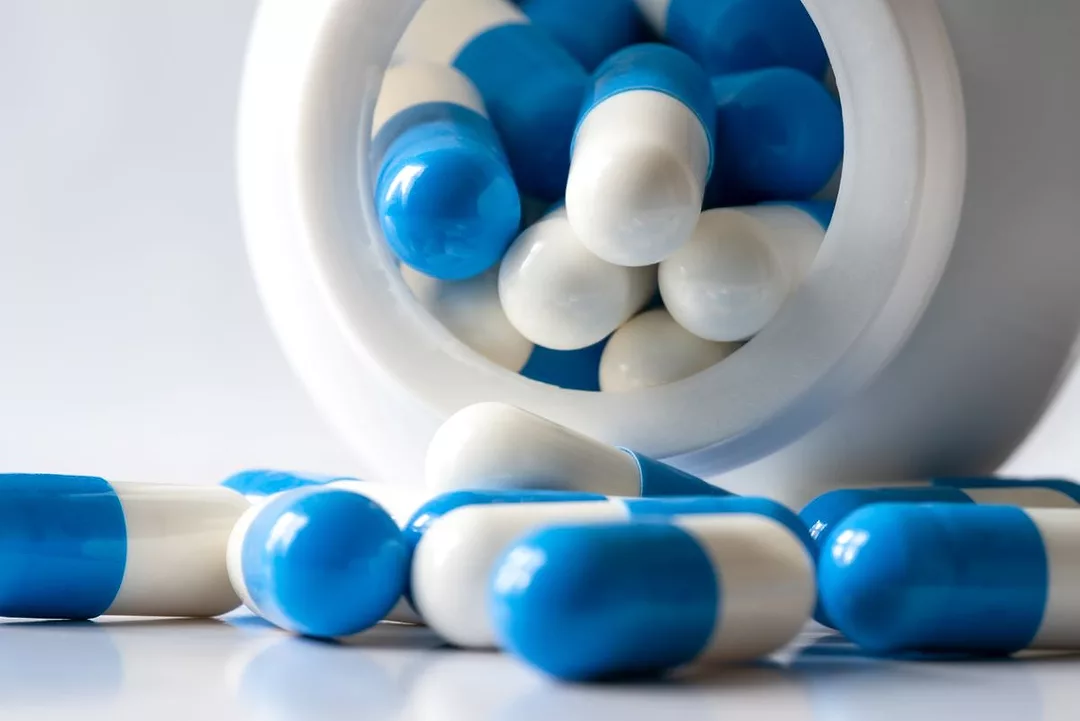 An open bottle spills capsules of amoxicillin antibiotics onto a table