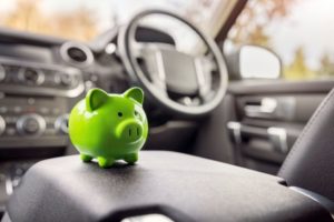 A BRIGHT GREEN PIGGY BANK SITS ON THE SEAT OF A TRUCK CAB INTERIOR