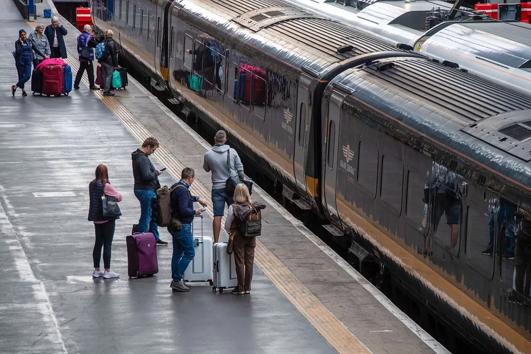 PASSENGERS ON A PLATFORM WAIT TO BOARD A TRAIN