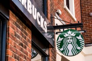 A STARBUCKS SIGN HANGS AGAINST A BRICK WALL OUTSIDE A STORE