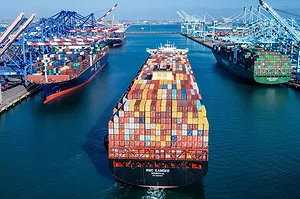 A LOADED CONTAINER SHIP ENTERS A BUSY PORT CHANNEL
