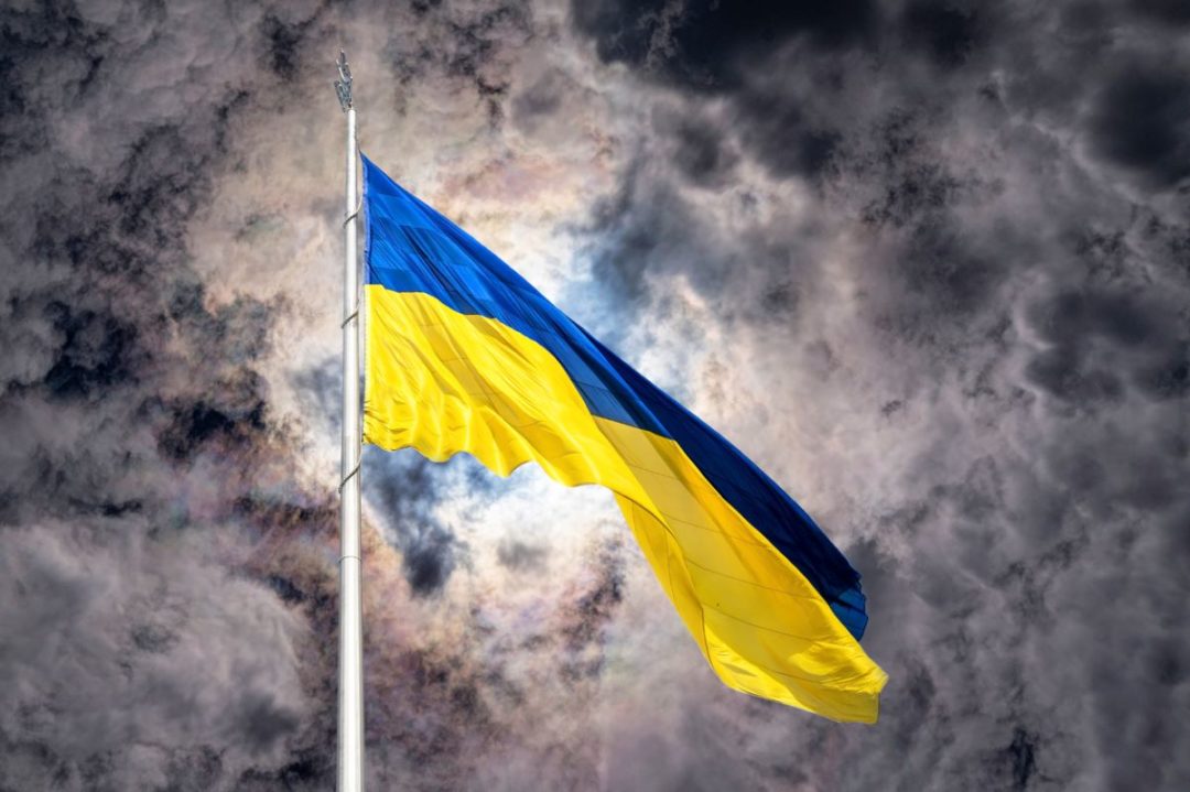 A UKRAINE FLAG FLIES AGAINST A SKY  OF CLOUDS AND LIGHT DIFFRACTED BY ICE CRYSTALS