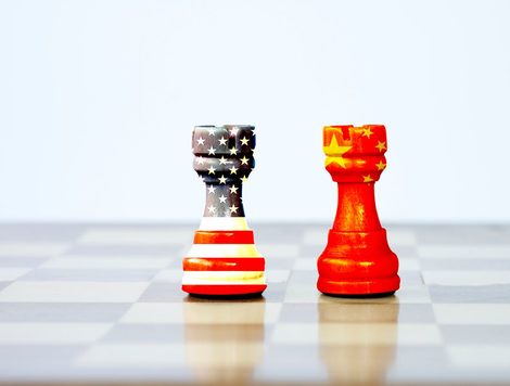 TWO CHESS PIECES ONE BEARING THE FLAG OF CHINA, THE OTHER BEARING THE FLAG OF THE US, FACE EACH OTHER ON A CHESS BOARD
