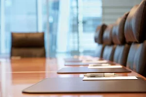A SHORT FOCAL LENGTH PHOTO OF A LONG BOARDROOM TABLE, CLUSTERED BY EMPTY LEATHER CHAIRS