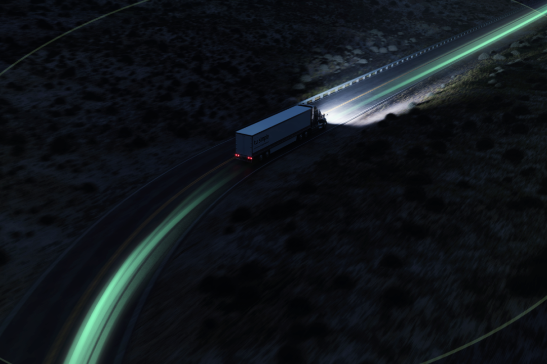 AN AERIAL SHOT OF A TRUCK DRIVING AT NIGHT, ITS HEADLIGHT SPREADING A BEAM OUT INTO THE DARK