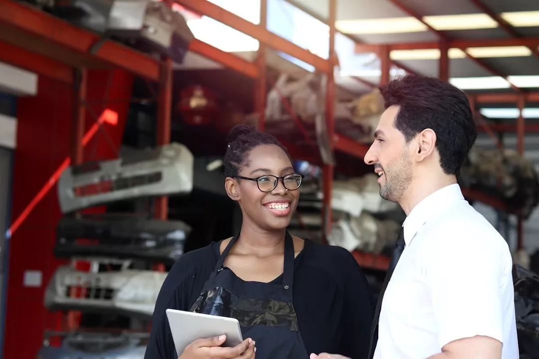 A WHITE MAN AND A WOMAN OF COLOR TALK AND SMILE IN A WAREHOUSE