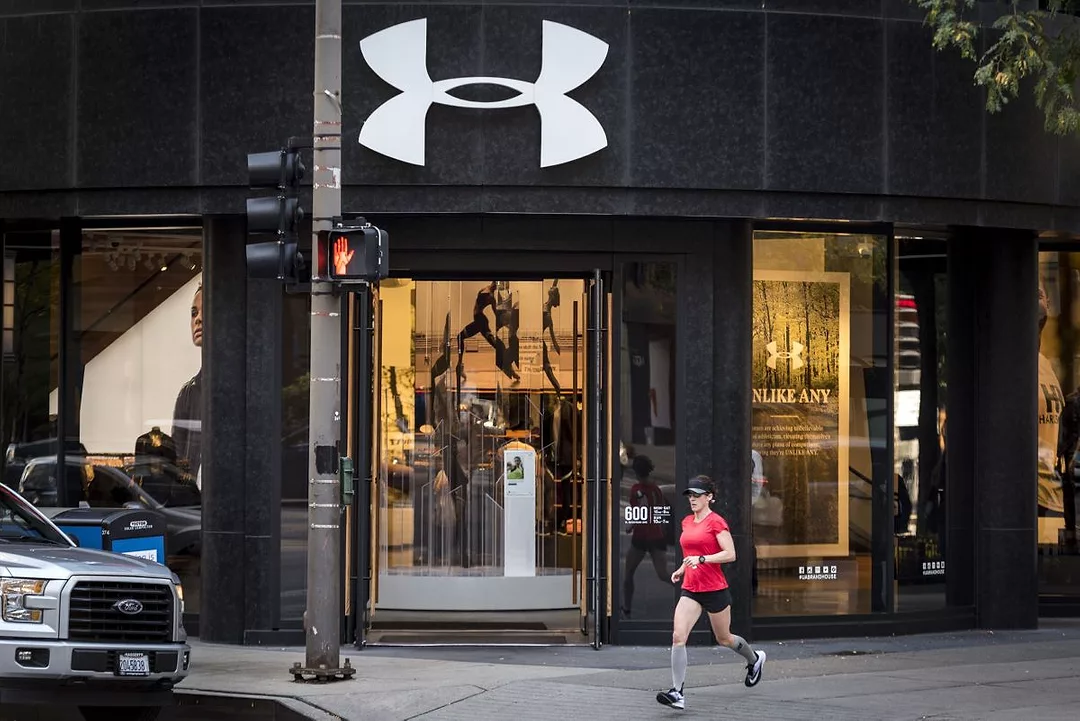 A RUNNER JOGS PAST AN OPEN STORE BEARING THE UNDER ARMOUR LOGO