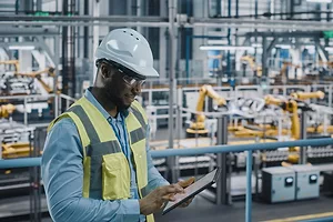 A WORKER CONSULTS A CLIPBOARD IN A FACTORY