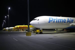 A LINE OF CARGO PLANES SITS AT NIGHT ON THE TARMAC, THE NEAREST ONE BEARING THE PRIME AIR LOGO