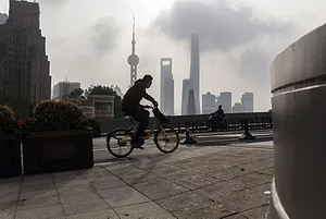 A BICYCLIST RIDES BENEATH THE SHANGHAI SKYLINE