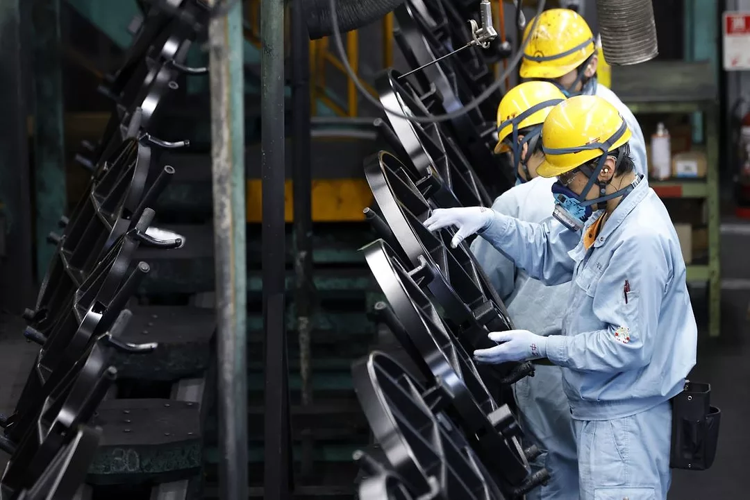 WORKERS IN OVERALLS AND MASKS WORK ON METAL OBJECTS