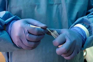 GLOVED HANDS PLACE A SWAB INTO A TEST TUBE