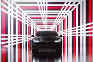 A SHINY BLACK CAR SITS IN A DAZZLING TUNNEL OF RED AND WHITE LIGHTS